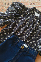 Flat lay of the Woodford Top and dark denim jeans from the JKB X LILYA collection. 