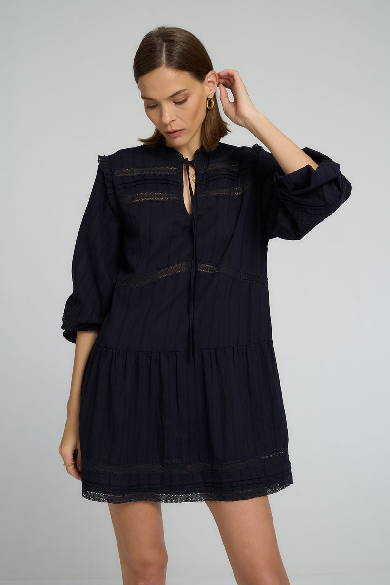 Model wearing Azalea Lace Mini Dress in Navy with adjustable tie neckline
