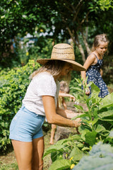 Side view of the Chamomile Short in Light Denim worn in the garden in Hawaii. 