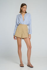 Model wearing sand cotton A-line shorts and striped chambray shirt by LILYA