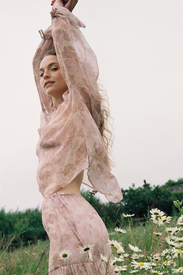 Woman in a floral long sleeve blouse outfit standing in a field with flowers