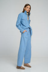 Breathable light blue chambray trousers featuring pleats, contrast stitching, and pockets