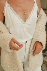Close up photo of satin white cami top worn with jacket