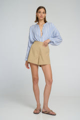 Model wearing LILYA Ginger Shirt in pale blue chambray stripes paired with Anise Short