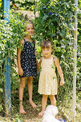 Jess's daughters wearing the girls pinafore dresses from the LILYA X JKB collaboration in their garden. 