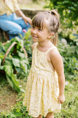 Lila Kids Dress in Yarrow Yellow with crossover straps and a pinafore silhouette.