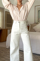 Woman wearing a striped long sleeve shirt and creme pants