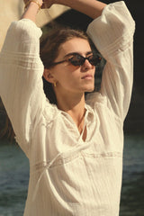 Woman in a white outfit with sunglasses by the water
