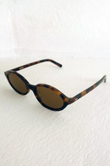 Sunglasses with tortoiseshell frame on a white textured background