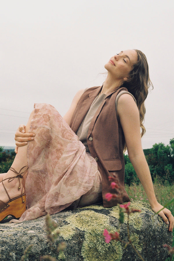 a woman wearing chocolate vest and moon floral maxi skirt