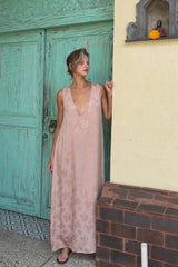 A woman wearing a sleeveless dusty pink floral satin dress, perfect for a long lunch. 