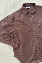 A flatlay image of a brown pinstripe blouse by Lilya