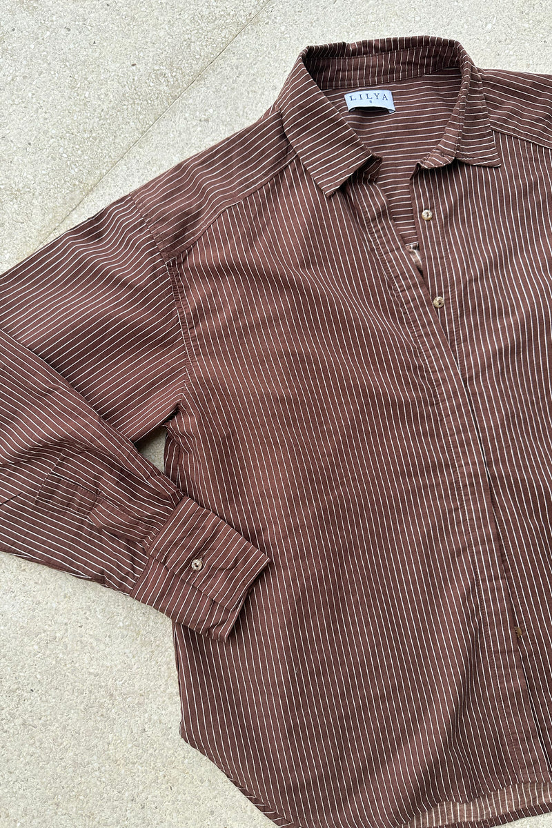 A flatlay image of a brown pinstripe blouse by Lilya
