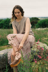 Woman sitting on a rock in a field with flowers wearing floral maxi skirt
