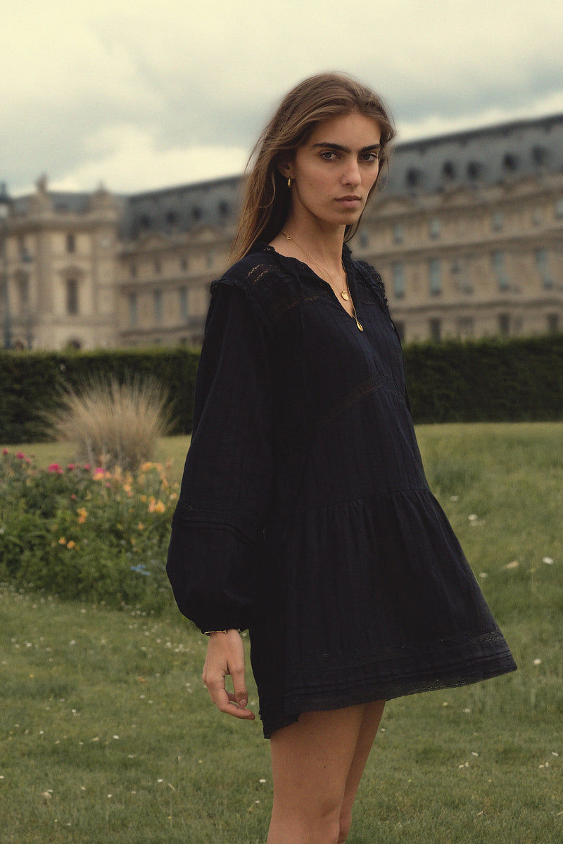 Side view of a navy cotton mini dress with lace detail