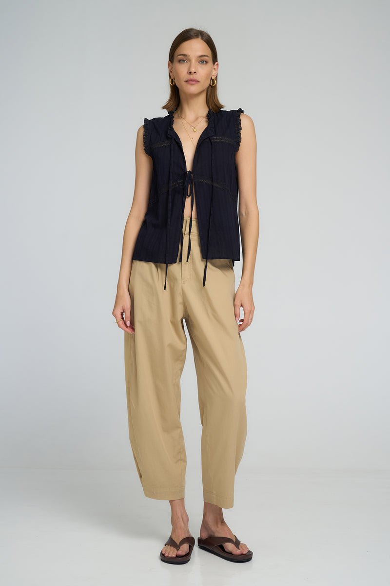 Model wearing LILYA Jupiter Lace Top in navy cotton with lace trim details and tie front styling