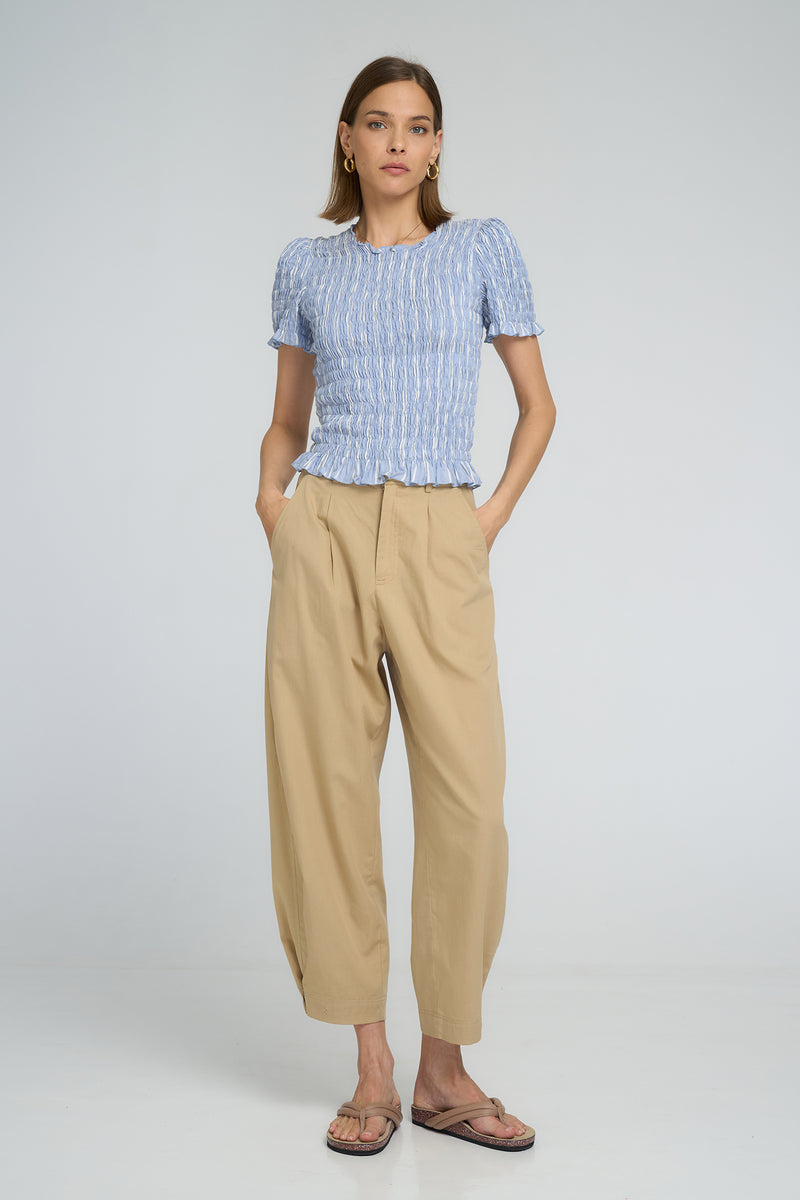 Model wearing LILYA Raincloud Top in pale chambray stripes paired with relaxed sand Utility Pants.