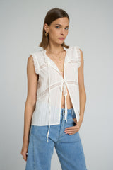 Sleeveless white cotton lace top styled casually with relaxed denim jeans