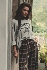 Model wears vintage grey marle sweater with large logo in relaxed fit with check pants