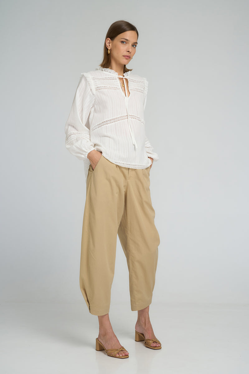 Boho-style white lace top featuring tie neck design and relaxed long sleeve fit